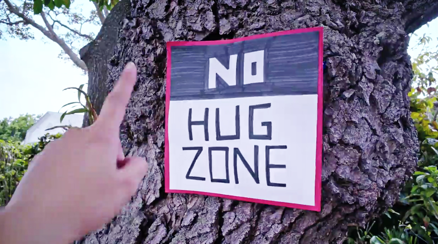 Finger points to "No Hug Zone" sign